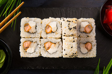 Set of sushi rolls with wasabi and ginger on a black background. Japanese oriental cuisine