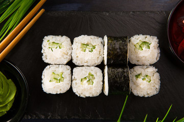Set of sushi rolls with wasabi and ginger on a black background. Japanese oriental cuisine