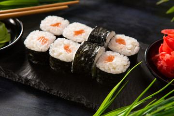 Set of sushi rolls with wasabi and ginger on a black background. Japanese oriental cuisine