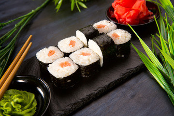 Set of sushi rolls with wasabi and ginger on a black background. Japanese oriental cuisine