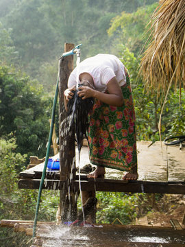 Jeune fille Lahu se lavant les cheveux dans un village de la r&eacute;gion de Chiang Ra&iuml;, Tha&iuml;lande.