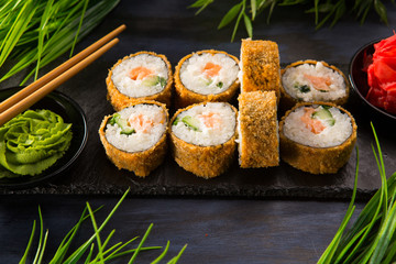 Set of fried sushi rolls with wasabi and ginger on a black background. Japanese oriental cuisine