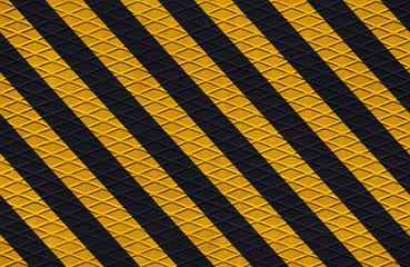 black and yellow safety hazard attention warning stripes on diamond metal texture