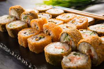 Set of baked sushi rolls with wasabi and ginger on a black background. Japanese oriental cuisine