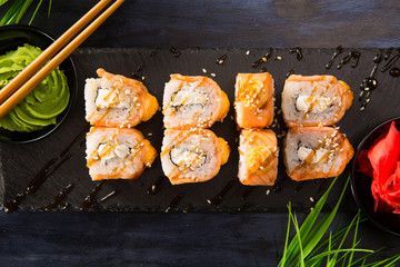 Set of baked sushi rolls with wasabi and ginger on a black background. Japanese oriental cuisine