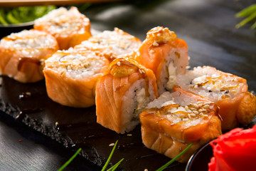Set of baked sushi rolls with wasabi and ginger on a black background. Japanese oriental cuisine