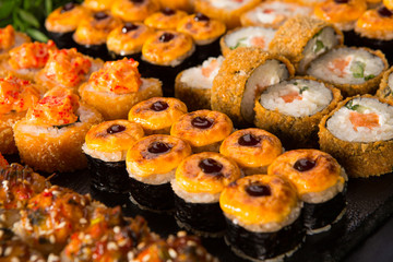 Set of baked sushi rolls with wasabi and ginger on a black background. Japanese oriental cuisine