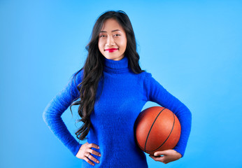 Young pretty woman with basketball in hand isolated on blue background