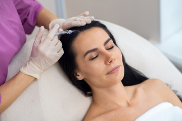 Obraz na płótnie Canvas Businesswoman closing eyes while having mesotherapy injection