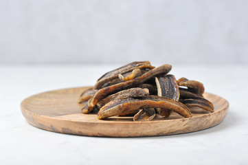Sun-dried bananas on a wooden plate.  Light background.  Free space for text.