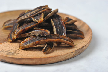 Sun-dried bananas on a wooden plate.  Light background.  Free space for text.  Close-up.