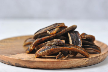 Sun-dried bananas on a wooden plate.  Light background.  Close-up.