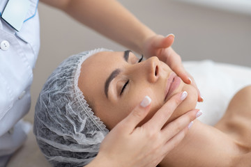 Fototapeta na wymiar Woman closing her eyes while enjoying face massage