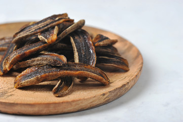 Sun-dried bananas on a wooden plate.  Light background.  Free space for text.  Close-up.