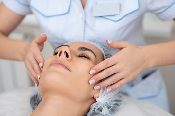 Fototapeta na wymiar Beauty doctor doing face massage for client lying and enjoying