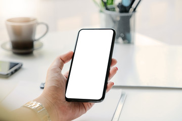 Woman hand holding smartphone on workplace. Blank screen mobile phone for graphic display montage