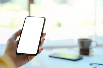 Woman hand holding smartphone with blur bokeh. Blank screen mobile phone for graphic display montage