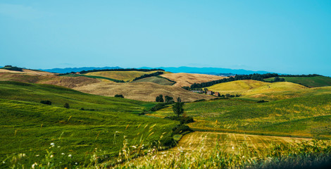 Beautiful view in Tuscany, Italy. Rural landscape. Countryside hills and meadows, green and yellow fields and sky. Beautiful world.