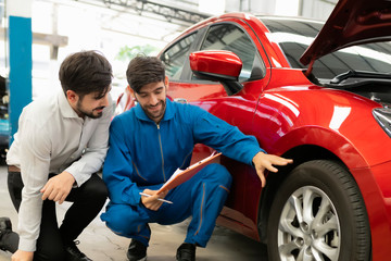 Fototapeta na wymiar A mechanic male handsome smiling maintenance service repair car to customer in garage. Automotive technician are checking tires with customers. concept checklist car vehicle repair maintenance..
