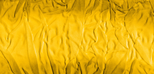 Vibrant yellow texture of binding crumpled fabric. Yellow textile background with natural folds....