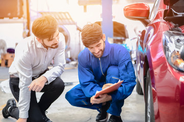 A mechanic male handsome smiling maintenance service repair car to customer in garage. Automotive technician are checking tires with customers. concept checklist car vehicle repair maintenance..