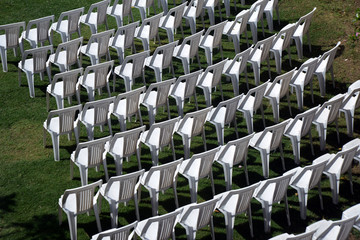 White plastic chairs arrangement on green lawn, in pleasant outdoor atmosphere