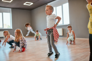 Group of cute little boys and girls studying modern dance in studio. Choreography class