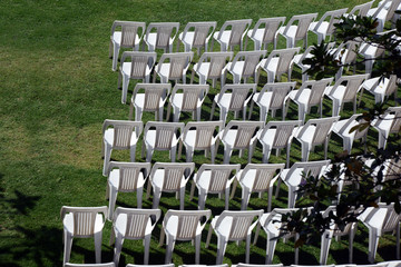 White plastic chairs arrangement on green lawn, in pleasant outdoor atmosphere