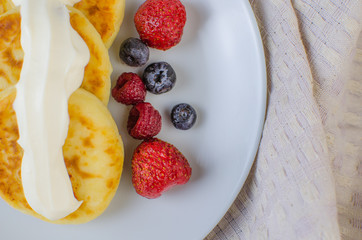 Pancakes with sour cream frozen blueberries and raspberries.