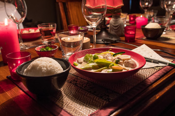 Thai green chicken & vegetables curry meal. Simmered in coconut milk. Thaï rice in a black ceramic bowl on the side. Close up of the food. Delicious asian meal.