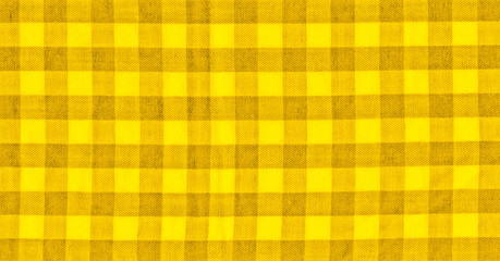 The texture of the bright yellow of binding gingham fabric. Yellow textile background. Fabric plaid. Close-up