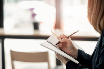 Closeup woman hand writing on notebook.