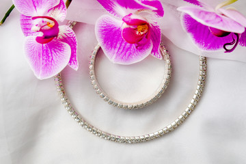 Bracelet and necklace on white fabric and purple Orchid