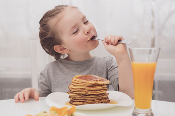 Milaya malen'kaya devochka yest bliny i zakrytymi ot udovol'stviya glazami69/5000Cute little girl eating pancakes and eyes closed with pleasure