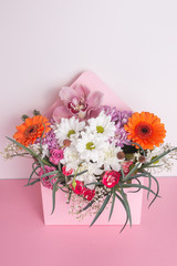 Bouquet of flowers in an original box on a white-pink background.