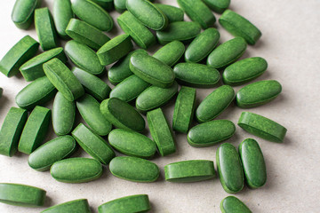 green pills chlorella on a gray background. nutritional supplements for a healthy diet
