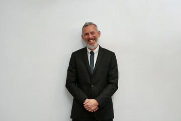 Happy business expert. Portrait of cheerful mature businessman in classic wear looking at camera and smiling while standing against grey background