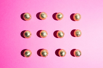 Chocolates in a multi-colored foil on a pink background