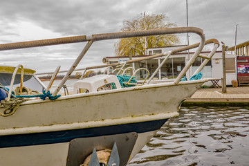  Front end of old metal boat moored up on the River Bure with the sailing club house in the...