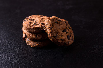 Appetizing chocolate chip cookies with slices of raisins on a black background.