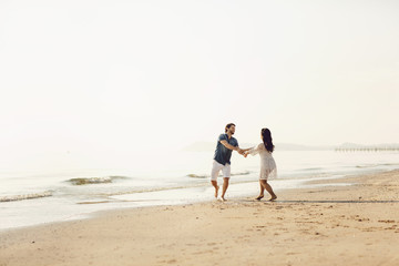 Fototapeta na wymiar Happy couple walking along the sea, holding hands. Love story