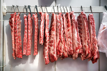 Row of pork ribs hanging in refrigerator