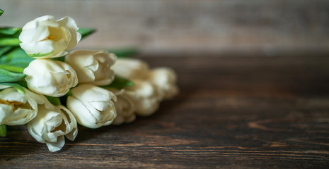 Spring flowers. Bouquet of white tulips on brown wooden table. Mother's Day and Valentines Day background. Rustic style. Copy space for your text.