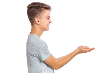 Portrait of cute smiling teen boy holding nothing - side view. Happy teenager with empty palms up - profile, isolated over white background. Child stretched out his hands - sign of begging or giving. - 329023173