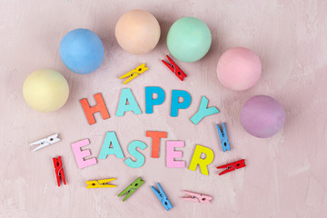 Decorated Happy Easter text with painted eggs on pink background - top view