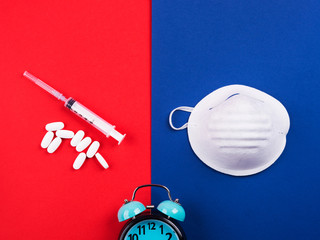 Epidemic danger prevention. Vaccine, treatment concept with masks, syringes and antibiotic pills on red and blue background. Novel coronavirus covid-19 from Wuhan, China