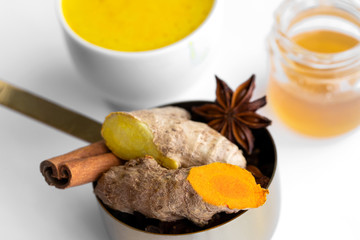 Ayurvedic warm beverage Golden drink in white cup with ingredients ginger, turmeric, spices and  honey on white  background.