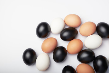 Many eggs of different colors on white background. Black, white and brown chicken eggs.