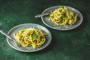 Two gray dishes of spaghetti pasta bucatini with pesto sauce and parmesan. Italian traditional...