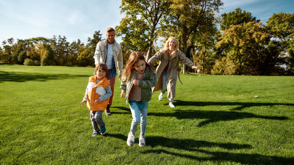 Obraz premium Sunny day. Excited family running outdoors on a sunny day